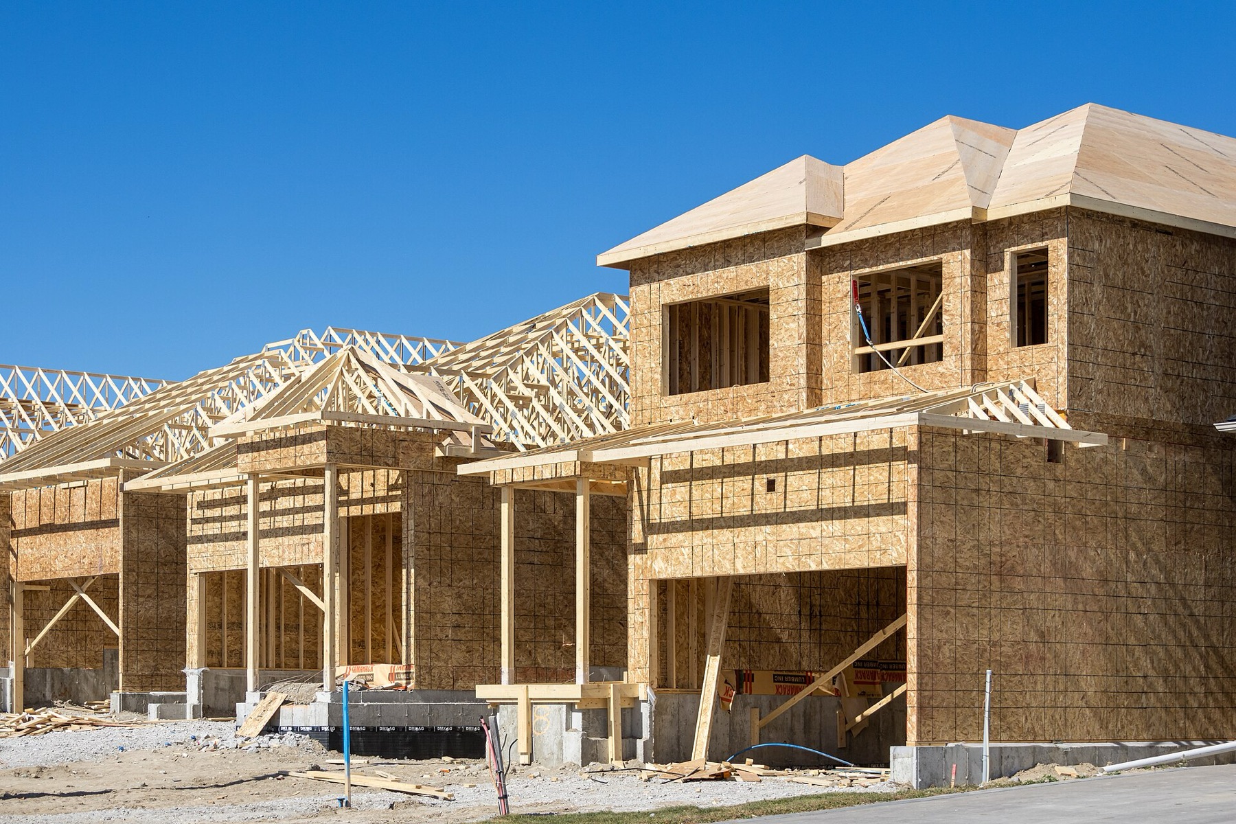 A row of new two-storey houses in wood framing with roof trusses going up