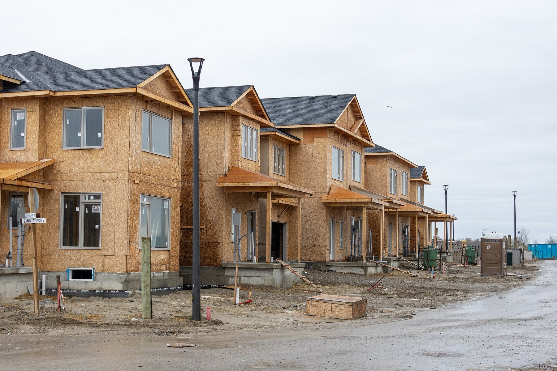 New houses in sheathing along an unpaved street
